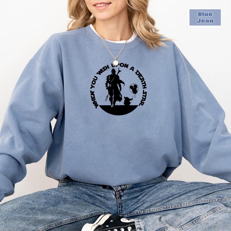 May include: A blue sweatshirt with a black graphic print of a character from the Star Wars franchise. The graphic features the text "When you wish upon a death star".