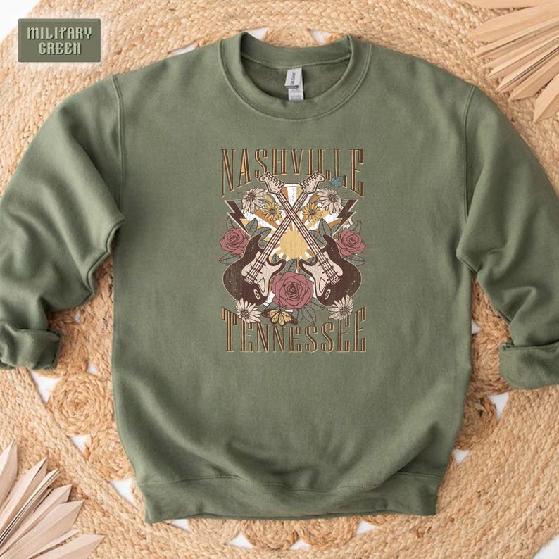 May include: A green sweatshirt with a graphic print of two guitars crossed over each other with flowers and the text "Nashville Tennessee".