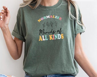 May include: A green t-shirt with the text "Normalize Minds of All Kinds" in colorful letters. The text is surrounded by small flower illustrations.