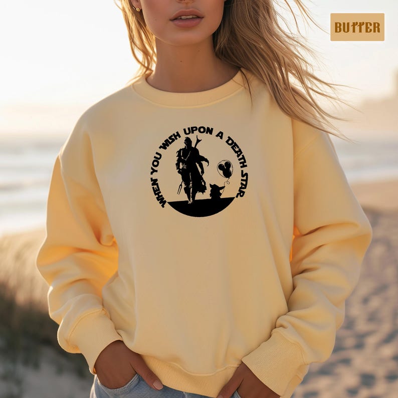 May include: A yellow sweatshirt with a black graphic print of a character from the Star Wars franchise. The graphic says "When you wish upon a death star".