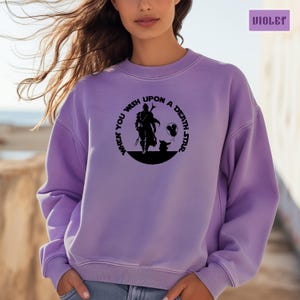 May include: A purple sweatshirt with a black graphic print of a character from the Star Wars franchise. The text on the graphic reads "When you wish upon a death star".