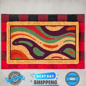May include: A coir doormat with a colorful abstract design featuring wavy lines and organic shapes in shades of red, orange, green, and purple. The doormat is framed with a black and red buffalo plaid border.