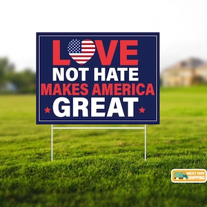 May include: A blue and white yard sign with the text "LOVE NOT HATE MAKES AMERICA GREAT" in red and white letters. The word "LOVE" has a red heart with an American flag inside.