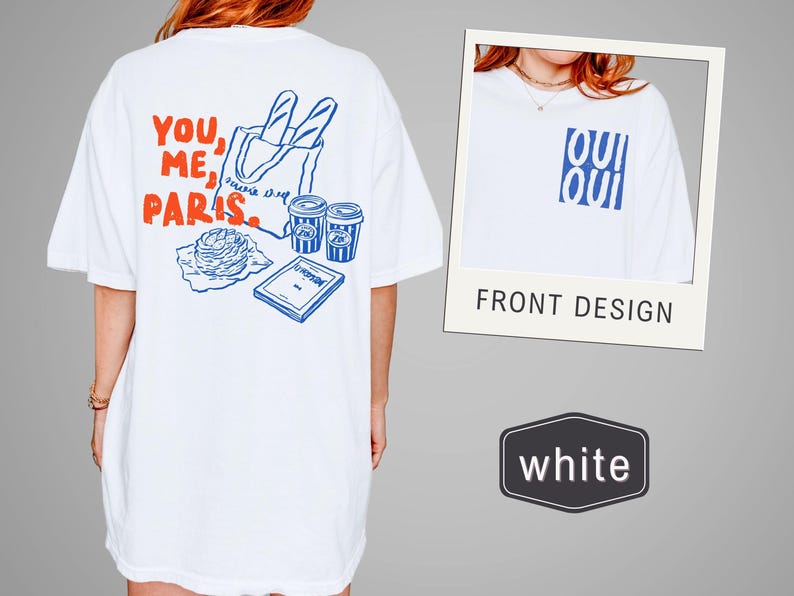 May include: White t-shirt with a blue and red graphic. The back design features the text "YOU, ME, PARIS" with illustrations of a baguette, coffee cups, and a pastry. The front design has the word "OUI" in blue.