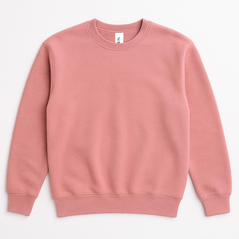 May include: A solid-colored, crew neck sweatshirt in a dusty rose hue. The long-sleeved top has a ribbed hem and cuffs. The brand name is visible on the neck. This casual apparel item is suitable for everyday wear.