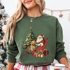 May include: A green Christmas sweatshirt with a vintage illustration of Santa Claus and a dog riding in a sleigh with presents. The text "Military Green" is visible at the bottom of the image.