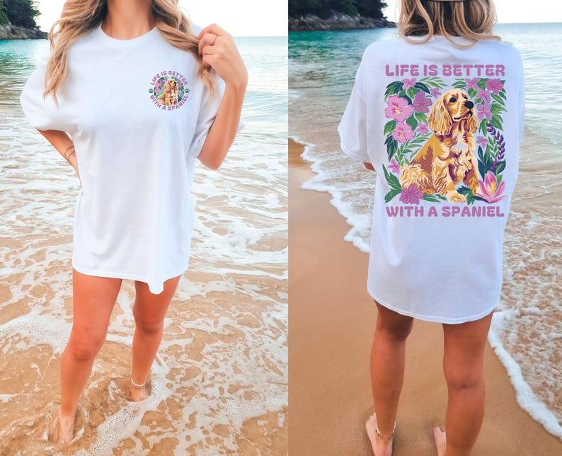 Op de afbeelding: Wit T-shirt met een afbeelding van een spaniel-hond omringd door bloemen en de tekst "Life is better with a spaniel".