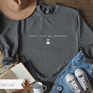May include: A charcoal grey sweatshirt with the text "Don't Get Me Started" and a small illustration of a mason jar.