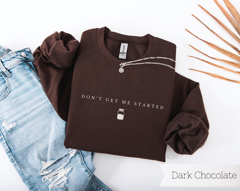 May include: A dark chocolate brown sweatshirt with the text "Don't Get Me Started" and a small milk jar graphic.
