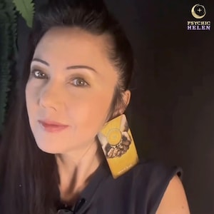 Pu&ograve; includere: Una donna con capelli scuri e trucco ha una carta dei tarocchi sulla spalla. La carta &egrave; gialla e presenta un'immagine di mani che tengono una moneta. Il testo "Psychic Helen" &egrave; visibile in alto a destra.