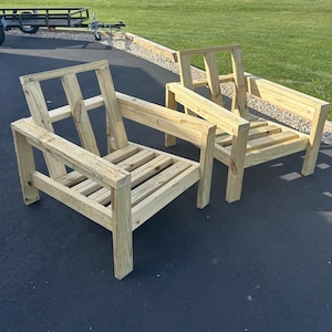 Puede incluir: Dos sillas de madera sin terminar con respaldos y asientos de listones. Las sillas son de madera natural y tienen un dise&ntilde;o simple y moderno.