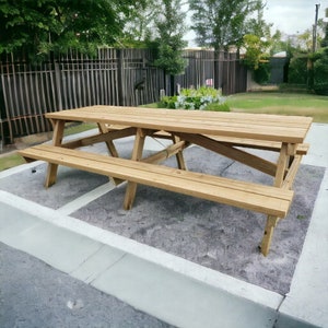 May include: A wooden picnic table with two benches. The table is made of natural wood and has a rustic look. The table is set on a concrete patio.
