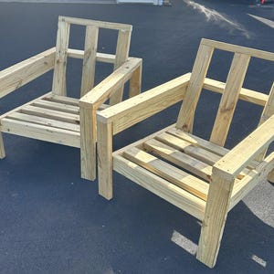 Puede incluir: Dos sillas de madera con respaldos y asientos de listones. Las sillas est&aacute;n hechas de madera sin tratar y tienen un dise&ntilde;o simple y r&uacute;stico.