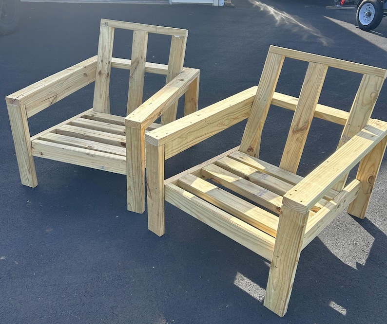 Puede incluir: Dos sillas de madera con respaldos y asientos de listones. Las sillas est&aacute;n hechas de madera sin tratar y tienen un dise&ntilde;o simple y r&uacute;stico.