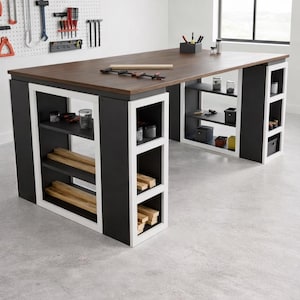 Op de afbeelding: Een grote, tweekleurige werkbank met een donkerbruin tafelblad en zwart-witte schappen. De werkbank heeft meerdere planken voor opslag en is ontworpen voor een werkplaats of hobbykamer. Gereedschap en benodigdheden zijn zichtbaar op de planken en het tafelblad.