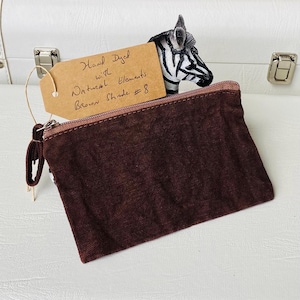 May include: A brown, hand-dyed zippered pouch with a tassel, and a tag that reads "Hand Dyed with Natural Elements Brown Shade #8". A zebra figurine is in the background.