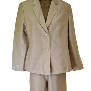 May include: A beige linen suit comprising a blazer and trousers. The blazer has a notched collar and two button fastenings. The trousers have a straight leg.