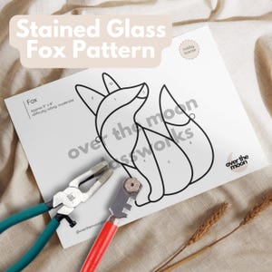 Puede incluir: Un patrón de zorro de vitral con secciones numeradas para un proyecto de artesanía. El patrón está impreso en papel blanco e incluye instrucciones para el trabajo del vidrio. La imagen también muestra herramientas para el vitral, incluyendo un cortador de vidrio y alicates.