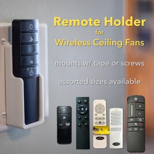 May include: A white remote holder for wireless ceiling fans, mounted on a wall. The holder is designed to accommodate various remote sizes. Text on the image reads "Remote Holder for Wireless Ceiling Fans, mounts w/ tape or screws, assorted sizes available."
