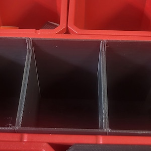 May include: Red plastic storage box with three black dividers. The box is empty.