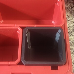 May include: Red plastic storage box with three compartments. The top compartment is empty, the middle compartment is red, and the bottom compartment is black.