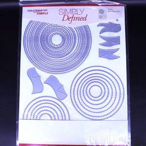 Puede incluir: Un paquete de formas troqueladas para scrapbooking. Incluye círculos de varios tamaños y formas decorativas. El paquete está etiquetado como "Simply Defined" y "Scrapbooking Made Simple".