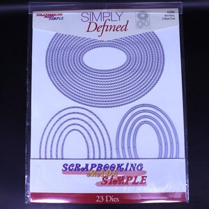 Puede incluir: Un paquete de troqueles de scrapbooking con el texto "SIMPLY Defined" y "SCRAPBOOKING MADE SIMPLE". Los troqueles son formas ovaladas y arqueadas con bordes festoneados. El paquete contiene 23 troqueles.