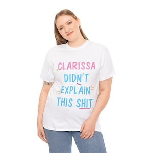 May include: White t-shirt with the text "Clarissa Didn't Explain This Shit" in pink, blue, and yellow lettering.