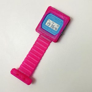 May include: A pink 3D printed Casio F-91W watch with a digital display showing the time 19:36:46. The watch has a black strap with a textured surface.