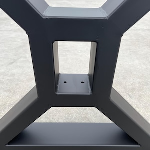May include: Black metal table base with a triangular design and a rectangular opening in the center. The base has two holes on the top.