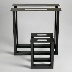 May include: Black metal table legs in a minimalist design. The set includes two large rectangular legs and a smaller, square-shaped leg set. Each leg has a series of horizontal bars and a handle-like cutout.