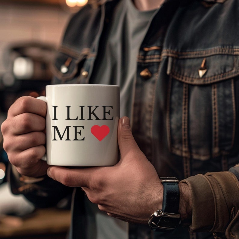 white coffee mug held by man with words i like me and a heart from the movie deadpool and wolverine