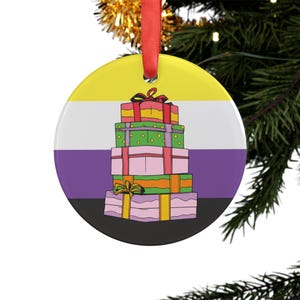 May include: A round ceramic ornament featuring a horizontal non-binary pride flag background of yellow, white, purple, and black stripes. Centered on the flag is a vertical stack of five colorful gift boxes tied with ribbons and bows.