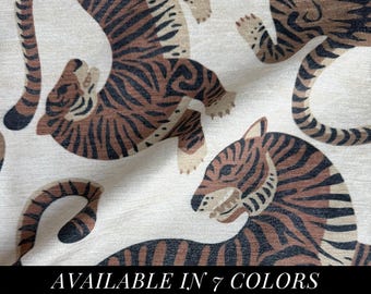 May include: A fabric featuring a repeating pattern of tigers in shades of brown and black on a cream-colored background. The tigers are depicted in various poses with visible stripes and paws. A black banner at the bottom displays the text AVAILABLE IN 7 COLORS.