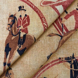 May include: Tan fabric with a repeating pattern of equestrian figures in red and brown. The design features riders on horseback, wearing riding attire, and a decorative circular border. The fabric has a textured appearance.