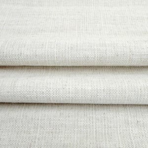 May include: A folded piece of off-white fabric with a visible woven texture. The material features a repeating pattern of vertical stripes created by subtle variations in the weave, resulting in a light beige and cream color palette throughout.