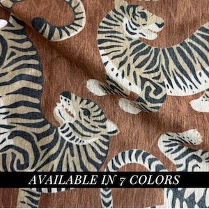 May include: Brown fabric with a repeating tiger pattern in black and tan. The tigers are stylized with stripes and spots. The text "AVAILABLE IN 7 COLORS" is displayed in a black rectangle at the bottom.