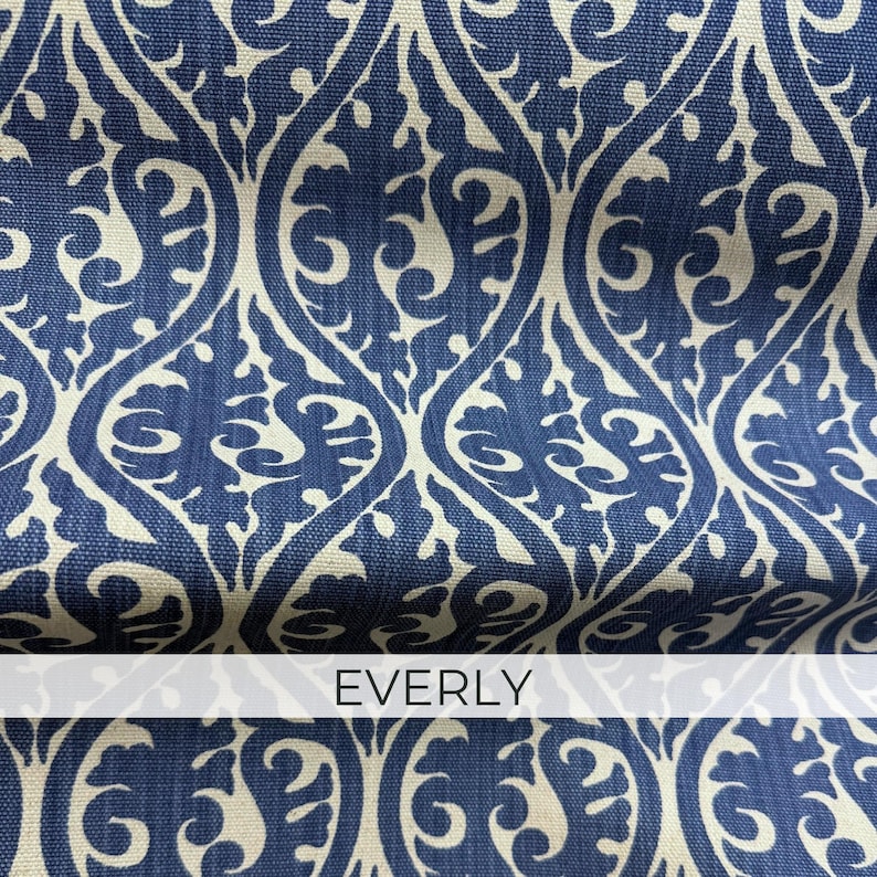 a close-up view of a fabric with a repeating pattern of blue and white swirls and curves. The fabric appears to be a type of upholstery or textile, with the word "EVERLY" written in white text on the fabric.