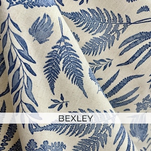 a close-up view of a fabric with a repeating pattern of blue fern leaves and other leaf-like designs. The fabric appears to be made of a light-colored material, possibly linen or a similar type of fabric. The text "BEXLEY" is visible in the image.