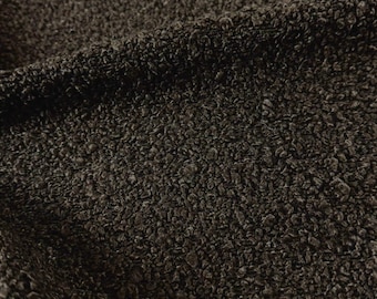May include: A dark brown fabric with a dense, textured, and curly pile surface. The material features a consistent, looped, and nubby appearance throughout, creating a deep, shadowed, and tactile finish across the entire visible textile area.
