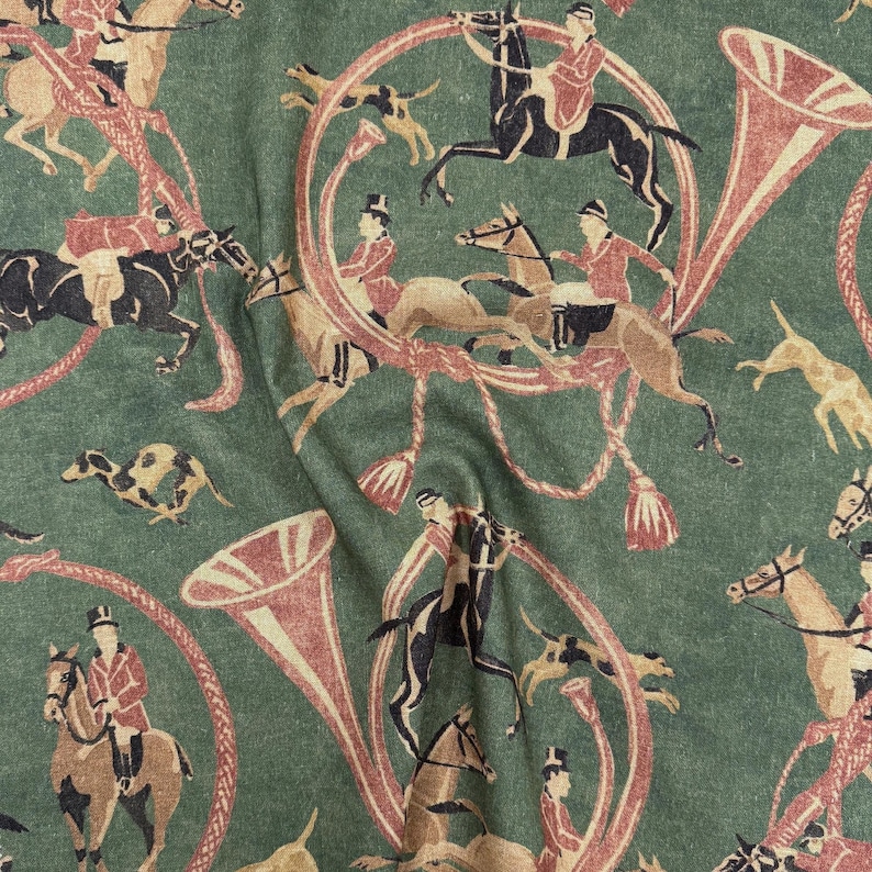 May include: Green fabric with a repeating pattern of equestrian figures, hounds, and hunting horns in shades of red, brown, and black. The design features riders on horseback, dogs, and decorative horn shapes.