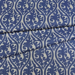 a close-up view of a fabric with a repeating pattern of blue and white swirls and leaves. The pattern is intricate and detailed, creating a visually striking design.