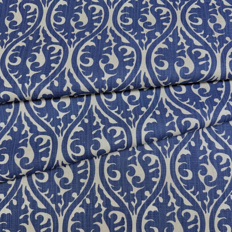 a close-up view of a fabric with a repeating pattern of blue and white swirls and leaves. The pattern is intricate and detailed, creating a visually striking design.