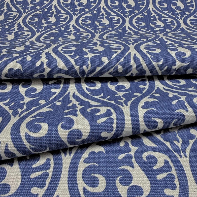 a close-up view of a fabric with a repeating pattern of blue and white swirls and curves. The pattern is intricate and detailed, creating a visually striking design.