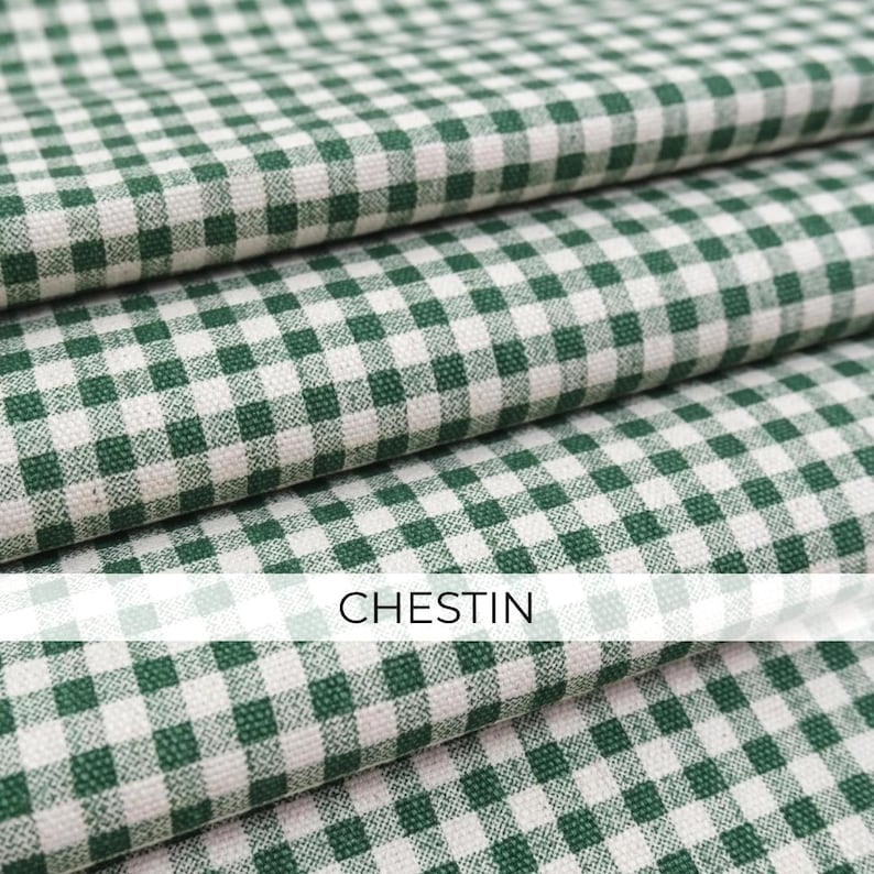 May include: A folded fabric featuring a classic green and white gingham check pattern. The textile displays a consistent woven texture throughout the layers. The word CHESTIN is printed in a clear, sans-serif font across the center of the image.