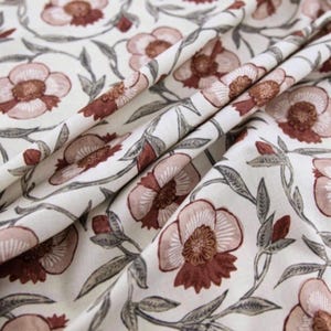 May include: White fabric with a repeating pattern of pink and brown flowers with grey leaves.