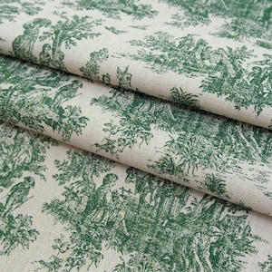 May include: A folded piece of off-white fabric featuring a repeating dark green toile de jouy pattern. The print depicts detailed pastoral scenes with figures, trees, and foliage, showcasing a classic monochromatic design on a textured textile.