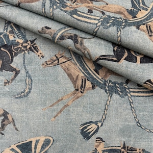May include: Close-up of a light blue fabric featuring a repeating pattern of horses and equestrian designs. The horses are illustrated in brown and black, with blue details. The fabric has a textured appearance.