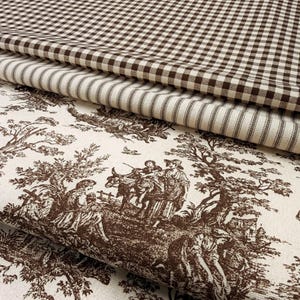 May include: A stack of fabric samples featuring various patterns. The top layer is a brown and white gingham check, followed by a cream and brown striped fabric. The bottom layer displays a brown toile de Jouy design with figures and landscapes.