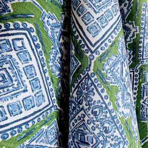 May include: A fabric featuring a repeating geometric pattern in shades of blue and white printed on a vibrant green background. The design consists of intricate square and diamond shapes with dotted borders and floral motifs within the lines.